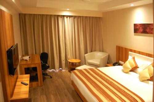 a hotel room with a bed and a desk and a television at Hotel Le Roi Raipur at Raipur Railway Station in Raipur