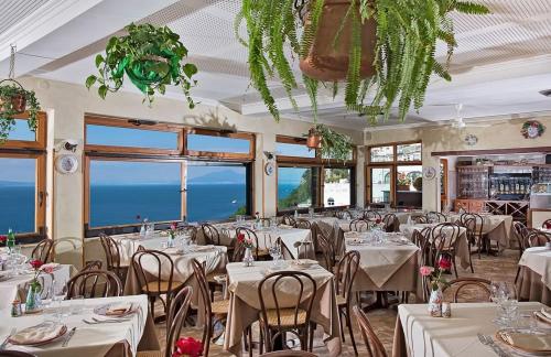 un restaurante con mesas y sillas blancas y ventanas en Da Giorgio en Capri