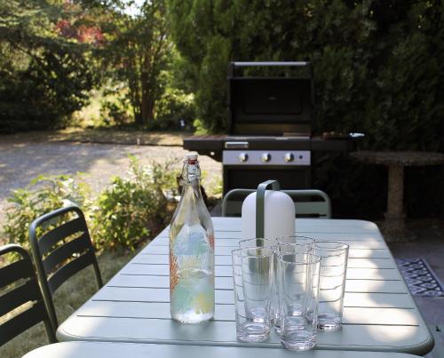 a white table with a bottle and glasses on it at Villa les Isards au cœur d'Argelès-Gazost in Argelès-Gazost