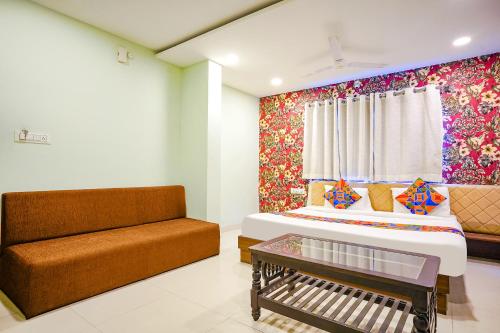 a bedroom with a bed and a couch and a window at FabHotel Uday Vilas in Indore