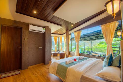 a bedroom with a large bed with a large window at Lifeline Villas - Luxurious 6BHK Pawna Lake View Villa in Lonavala