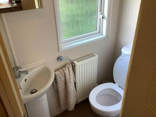 a bathroom with a toilet and a sink and a window at Beautiful 6 Berth Caravan With Wifi In Hampshire Ref 81337sb in Milford on Sea