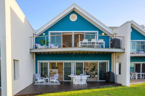 a blue house with a balcony with a table and chairs at Ocean View Villa, 2 bedroom in Mandurah