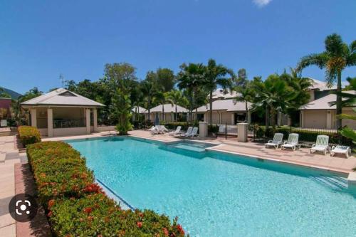 a large swimming pool with chairs and palm trees at Lahania by the Sea - JJ Place in Clifton Beach