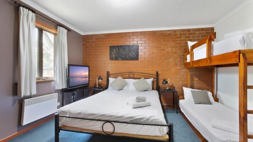 a bedroom with two bunk beds and a brick wall at Lindsay Lachen in Mount Hotham