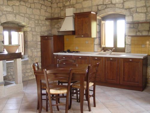 eine Küche mit einem Holztisch mit Stühlen und einem Waschbecken in der Unterkunft Le case di don Peppino in Pietre Nere San Zagaria