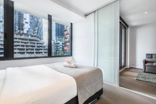 a bedroom with a large bed and large windows at Sakura Serviced Apartments in Melbourne
