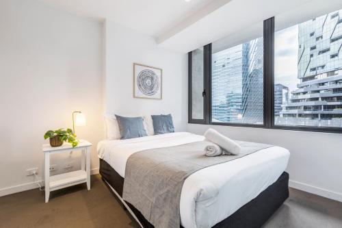 a white bedroom with two beds and a window at Sakura Apartment in Melbourne
