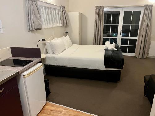 a hotel room with a bed and a kitchen at Anchor Lodge Motel in Coromandel Town