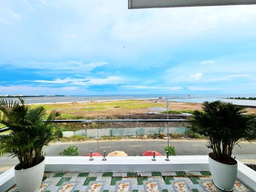 a view of a beach from a balcony with two palm trees at Seaside Hotel - Rach Gia in Rach Gia