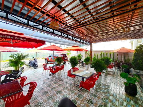 a patio with red chairs and tables and umbrellas at Seaside Hotel - Rach Gia in Rach Gia