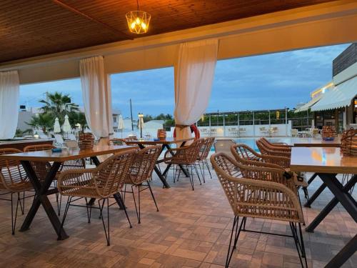 a patio with tables and chairs and windows at Newcastle Studios by Estia in Malia