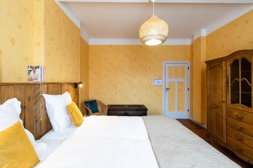 um quarto com uma grande cama branca e paredes amarelas em Maison spacieuse unifamiliale. Gîte La Clochette em Bastogne