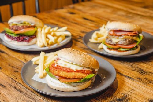 three plates of hamburgers and french fries on a table at Peppers Cradle Mountain Lodge in Cradle Mountain
