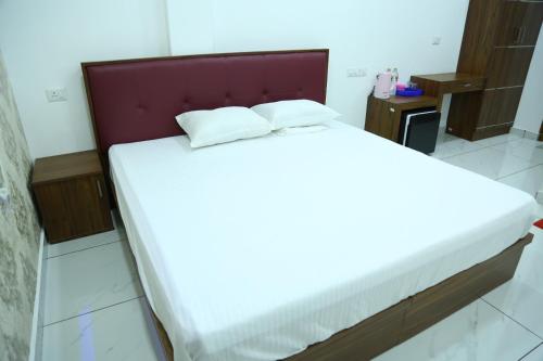 a large white bed with a red headboard in a room at Kurianplackal Residency in Alwaye
