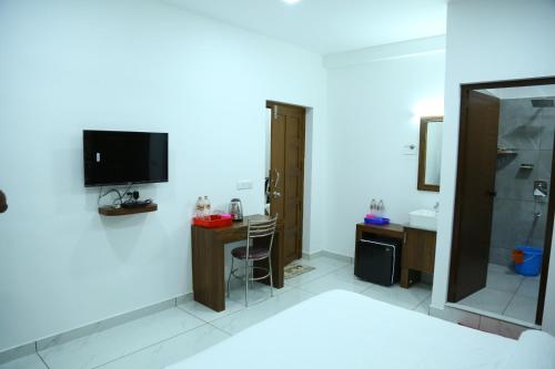 a room with a bathroom with a television and a sink at Kurianplackal Residency in Alwaye