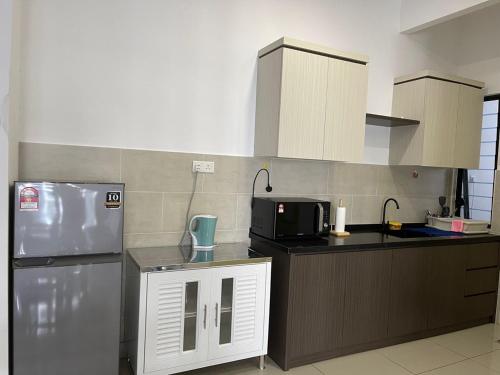 eine Küche mit einem Kühlschrank und einer Mikrowelle in der Unterkunft Atlantis Residence Batik Travel in Tranquerah