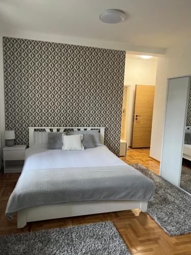 a bedroom with a large bed and a wall at Centar NS2 in Novi Sad