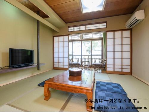 a living room with a table and a tv at Tabist Asanokan Annex Iroha Ise in Ise
