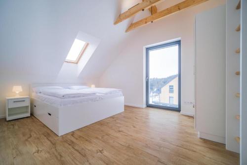 Dormitorio blanco con cama y ventana grande en Chata Lipno U Hajenky, en Lipno nad Vltavou
