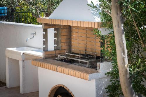 a outdoor kitchen with a grill and a sink at Villa Estrella with Heated pool in Aegina Town