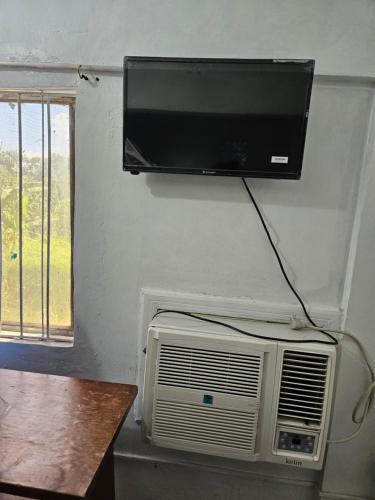 a tv hanging on a wall with a fan and a air conditioner at Antipolo Budget Hostel,Family Rooms in Antipolo