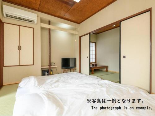 a bedroom with a white bed and a tv at Tabist Asanokan Annex Iroha Ise in Ise