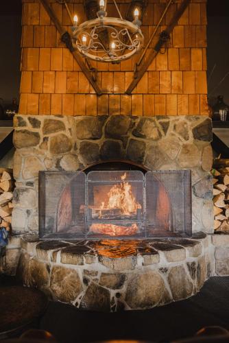 a stone fireplace with a fire in it at Peppers Cradle Mountain Lodge in Cradle Mountain
