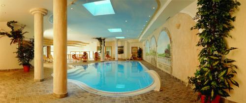 een groot zwembad in een grote kamer met zuilen bij Hotel Thaneller Stadl Bräu in Berwang