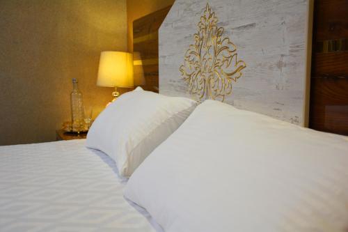 a bed with white sheets and pillows in a room at Khyber Guest House Swat in Saidu
