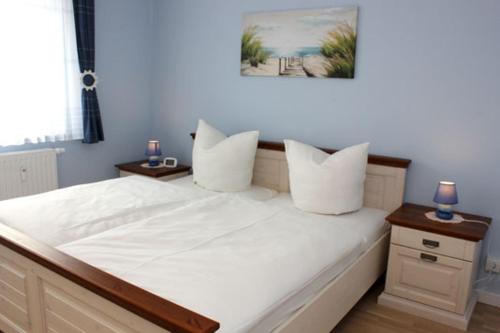 1 cama grande con sábanas blancas y almohadas. en Käptn Brass Appartement 17 Ostseeperle, en Dierhagen