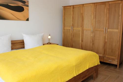1 dormitorio con cama amarilla y armarios de madera en Käptn Brass Villa 5 App 3 Strandrose, en Dierhagen