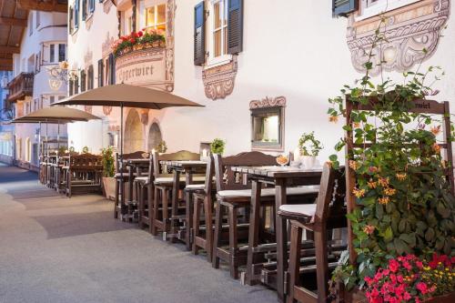 an outdoor restaurant with tables and umbrellas on a street at Eggerwirt Kitzbühel, Hotel & Restaurant in Kitzbühel