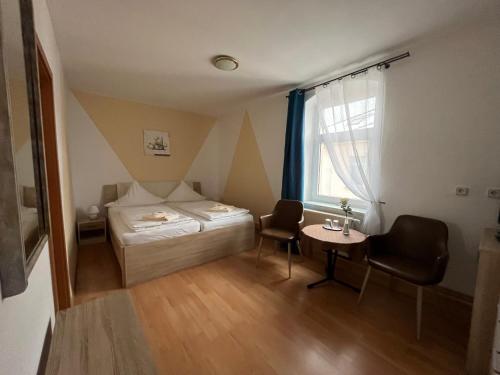 a room with a bed and a table and a window at Pension Am Renner in Dresden