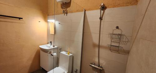 y baño con aseo, lavabo y ducha. en Bait Al Aali Guesthouse, en Al Ḩamrāʼ