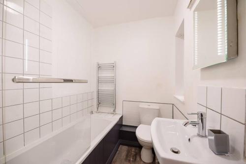 La salle de bains blanche est pourvue d'un lavabo et de toilettes. dans l'établissement 1 Abbey Mews, à Leiston