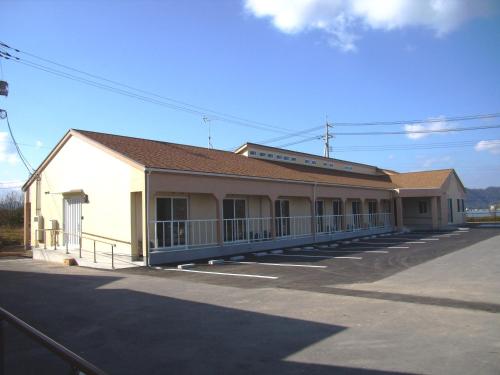 a large white building with a roof on a street at Cycle Guest House SHIOKAZE in Setoda