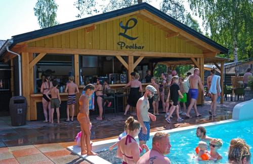 un grupo de personas de pie alrededor de una piscina en Forest Family 6 persoons op 5 sterren park, en Beekbergen