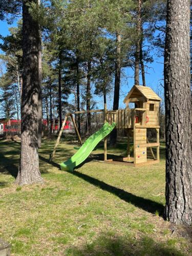 a playground with a green slide and a tree at Hotel Småland in Skillingaryd