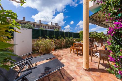 a patio with a table and chairs and flowers at Casa Ginebro in Font de Sa Cala