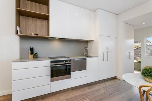 a kitchen with white cabinets and stainless steel appliances at Coogee Beach 2 Bedroom Apartment - CG226 in Sydney