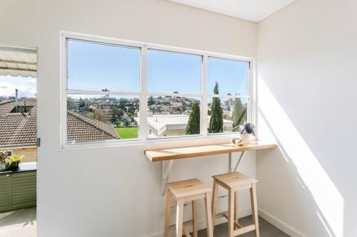 a room with a table and two stools in front of a window at Coogee Beach 2 Bedroom Apartment - CG226 in Sydney