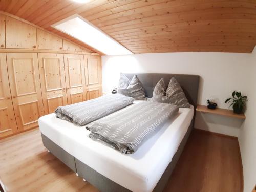 a bedroom with a white bed with a wooden ceiling at Haus Bacher Leogang in Leogang
