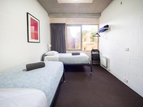 a hospital room with three beds and a window at YHA Apollo Bay Eco in Apollo Bay