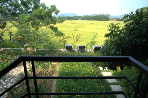 a view of a field from the balcony of a house at Greenfield Ecostay in Phong Nha