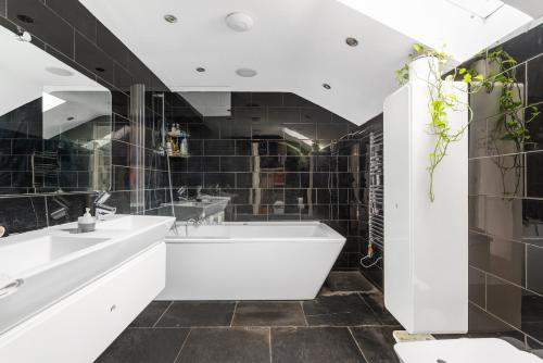 a bathroom with a white tub and black tiles at Studio for 3 with a private balcony in a Cubic house with outside pool in London