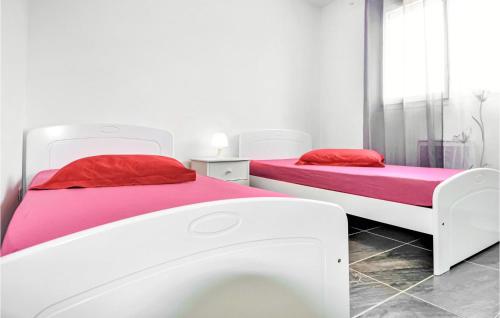 2 Betten mit roter und rosa Bettwäsche in einem Zimmer in der Unterkunft Awesome Home In Vallon Pont Darc With Outdoor Swimming Pool in Vallon-Pont-dʼArc