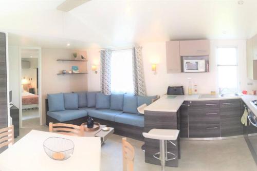 Una sala de estar con un sofá azul y una cocina. en Coquillages & Crustacés avec Piscine Chauffée & Plage, en Marennes