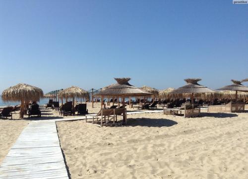 a beach with straw umbrellas and chairs on the sand at Premium complex Millennium 2 - Family apartment & Spa in Sveti Vlas