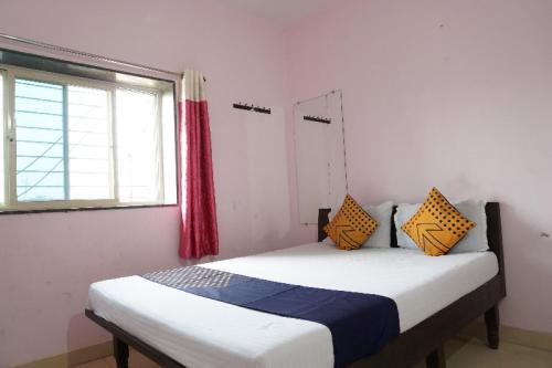 1 dormitorio con 1 cama con almohadas amarillas y azules en SPOT ON Hotel Aryan Lodging And Boarding, en Chākan